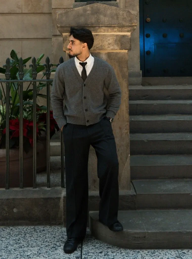 17 Winter Formal Outfits for Men That Look Sharp 2 a man posing in a Soft Grey Cardigan with Black Tie and Wide Trousers