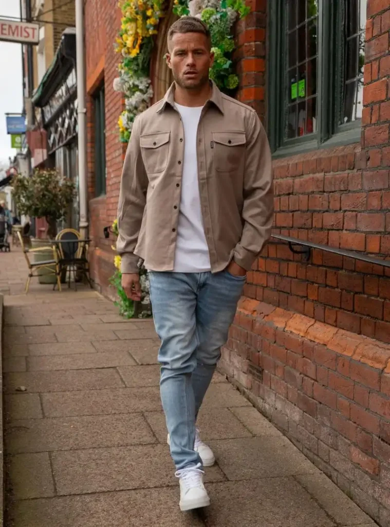 16 Fall Outfits With Jeans for Men You Can Actually Wear 4 a man walking in a Taupe Overshirt with Light Jeans and White Sneakers