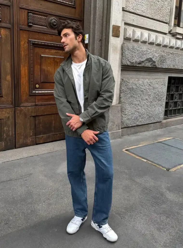 16 Fall Outfits With Jeans for Men You Can Actually Wear 6 a man posing in a Blue Jeans with an Olive Jacket