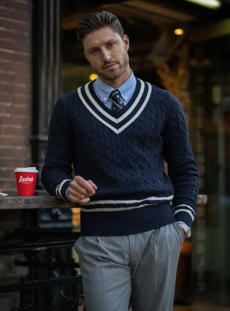 12 Smart Fall Business Casual Outfit Ideas to Look Sharp 6 a man posing in a Cable Knit Cricket Sweater with Club Tie and Grey Slacks