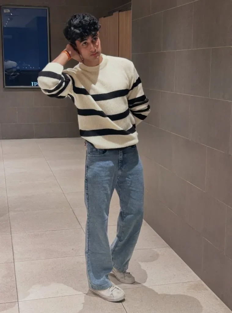 16 Fall Outfits With Jeans for Men You Can Actually Wear 12 a man wearing a Striped Cream Sweater with Relaxed Blue Jeans