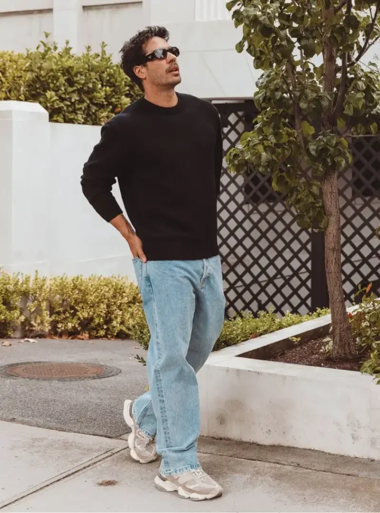 16 Fall Outfits With Jeans for Men You Can Actually Wear 13 a man posing in a Black Crewneck Sweater with Loose Light-Wash Jeans