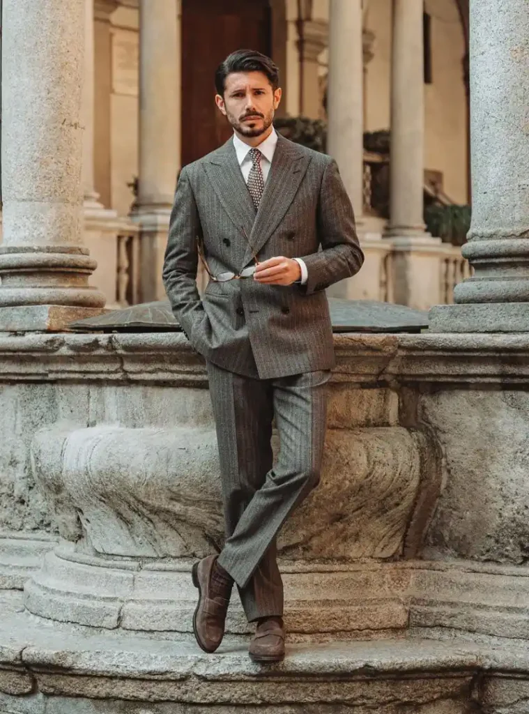 17 Winter Formal Outfits for Men That Look Sharp 13 A man wearing a Grey Double-Breasted Suit with Patterned Tie and Brown Loafers